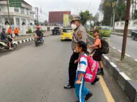 Atur Lalu Lintas Pagi, Satlantas Polres Tanah Karo Bantu Anak Sekolah Nyebrang Jalan
