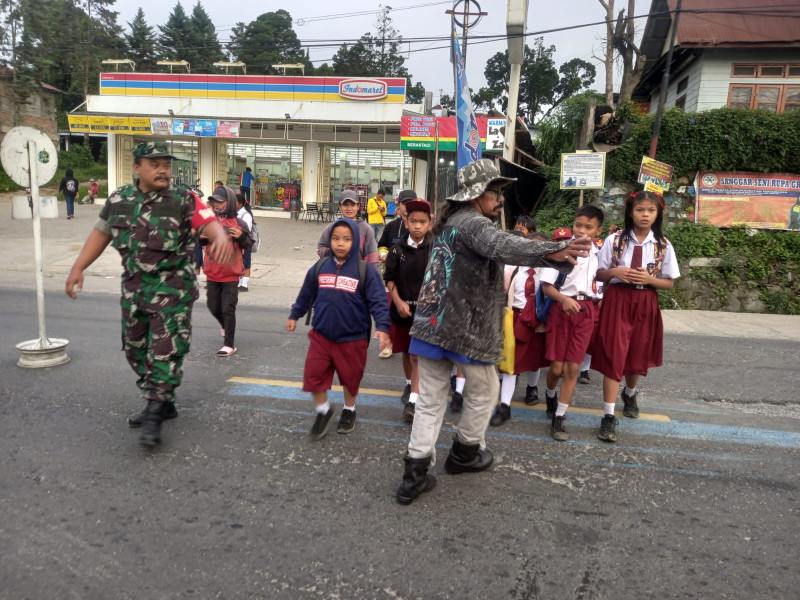 Kepedulian, Babinsa Koramil 03/Berastagi Bantu Seberangkan Anak Sekolah di Jalan Jamin Ginting